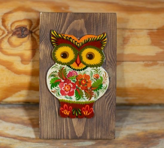 Rustic handcrafted owl wall decoration on brown wood, authentic ukrainian crafts